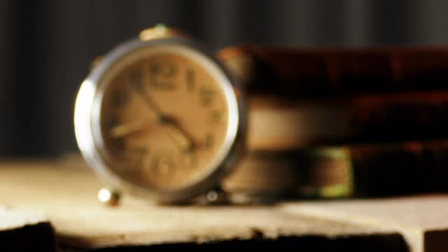 古董闹钟与旧皮革封面书木制桌子视频素材
