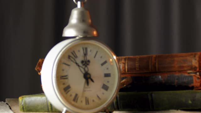 古董闹钟与旧皮革封面书木制桌子视频素材