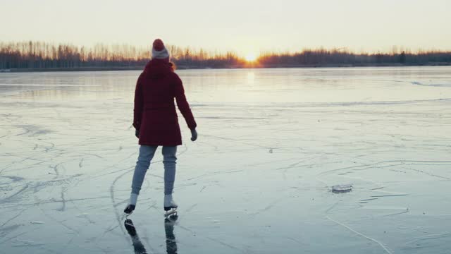 日落时分，女子在结冰的湖面上滑冰视频素材