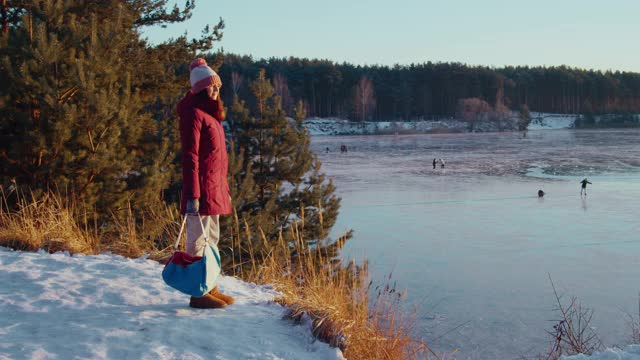 一个女人带着运动包来到一个冰湖上的溜冰场视频素材