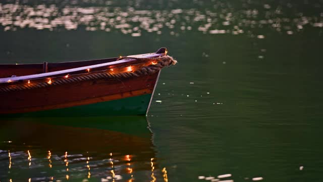 慢镜头:年轻女子坐在装饰华丽的小船上，灯光在湖面上飘浮视频素材