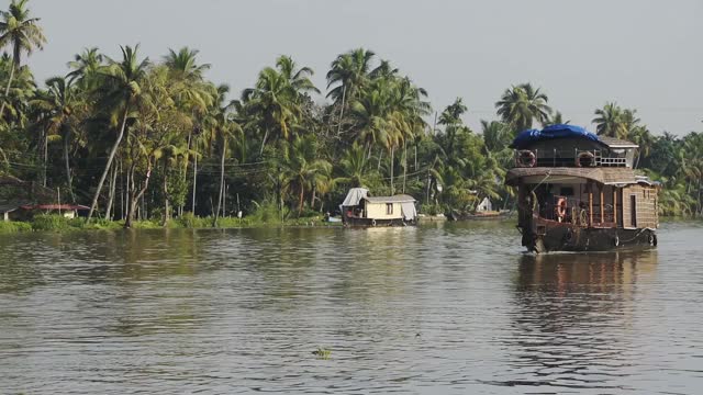 印度喀拉拉邦回水区，漂浮在棕榈树环绕的河上的船屋视频下载