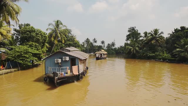 印度喀拉拉邦回水区，在棕榈树附近的河流上漂浮的船屋视频下载