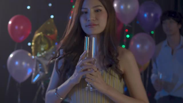 一个亚洲年轻女子在晚会上喝酒和大笑的4k视频。妇女们在圣诞节和新年互相庆祝。视频下载