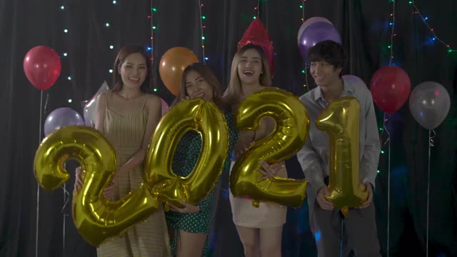 一群朋友，四个年轻的亚洲人，在一个房间里举办了一个小型派对。男人和女人在圣诞节和新年互相庆祝视频下载