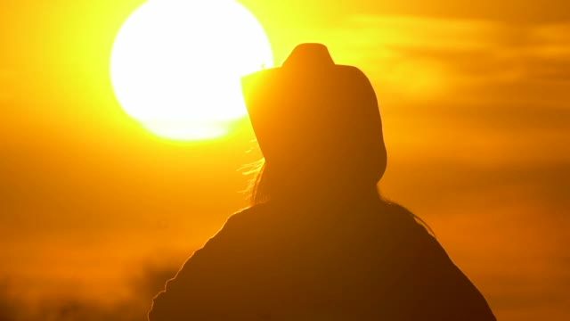 日落时戴着帽子的年轻女农民视频下载