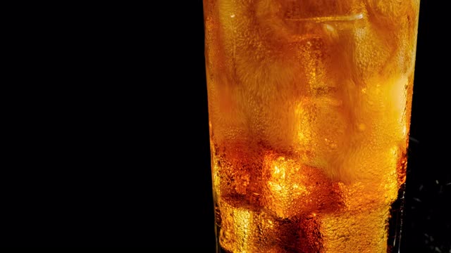 一杯可乐泡泡加冰块。可乐与冰和泡沫在玻璃上的黑色背景。视频素材