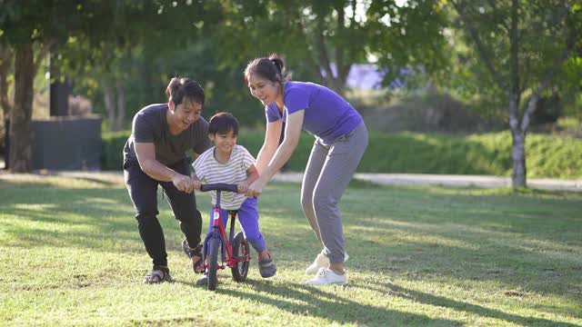 亚洲家庭教小男孩在公园骑自行车。视频素材