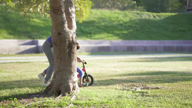 亚洲母亲教儿子骑自行车在公园。视频素材