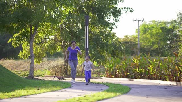 快乐的亚洲妈妈和儿子在公园，户外慢跑。视频素材