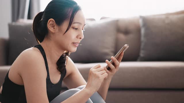 运动女性在家里使用智能手机视频素材