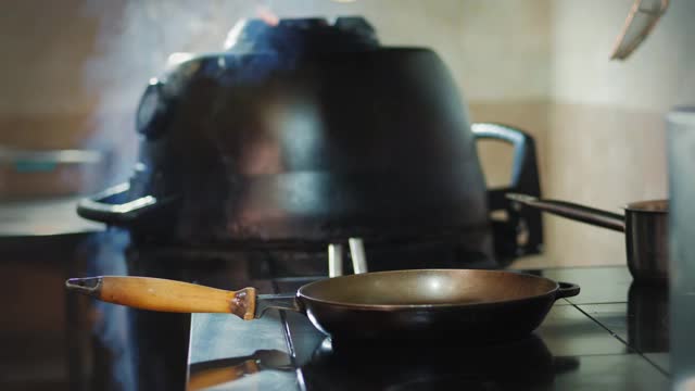 烹饪。厨师戴着防护手套，将食用油，植物油从瓶中倒入热煎锅中。煎炸食品视频素材