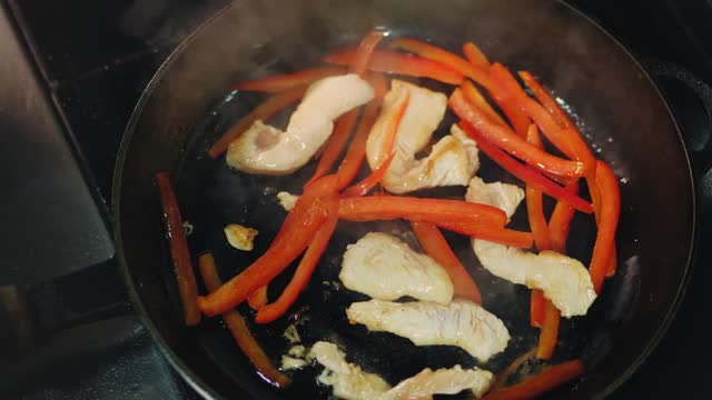 烹饪。特写镜头。肉片和蔬菜在平底锅里煎。前视图。烹饪视频素材