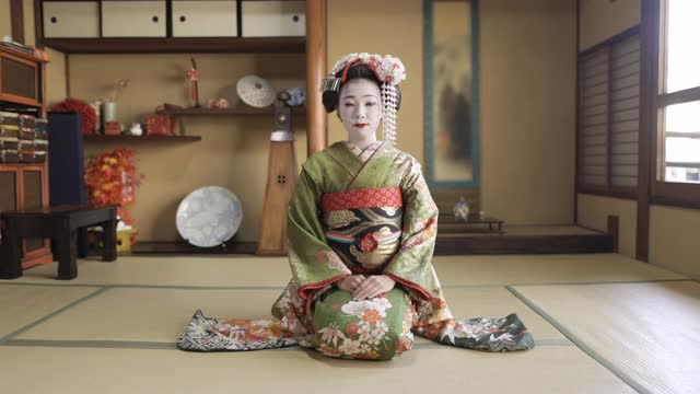 舞妓(训练中的艺妓)坐在高跟鞋上，在日式榻榻米屋里鞠躬视频下载
