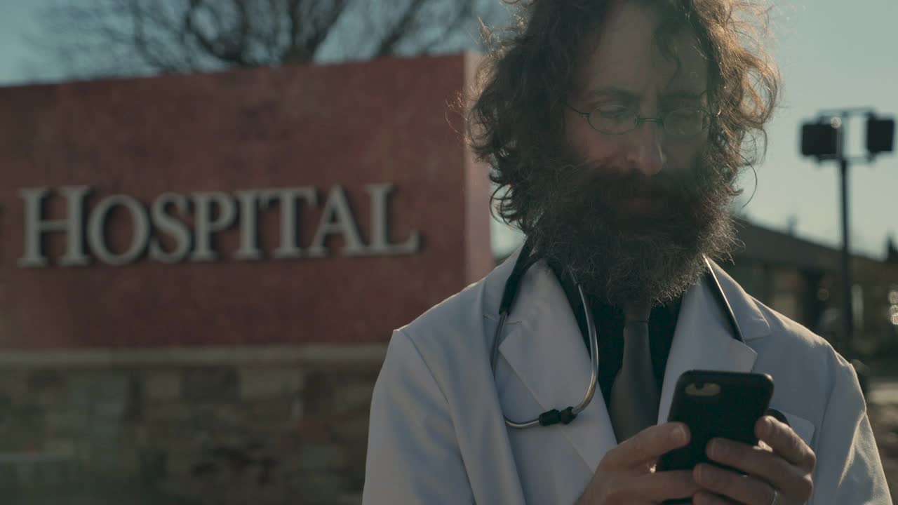 一个医生与他的手机在医院外沟通的特写视频下载