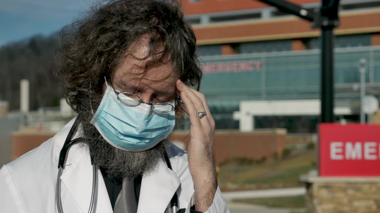 压力山大的男医生在医院前戴着口罩揉额头视频下载