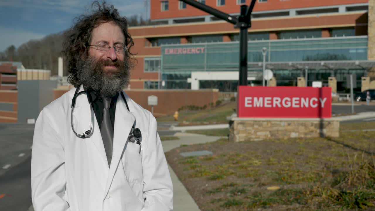 一个穿着实验室大褂戴着面具的男人在医院前和别人握手视频下载