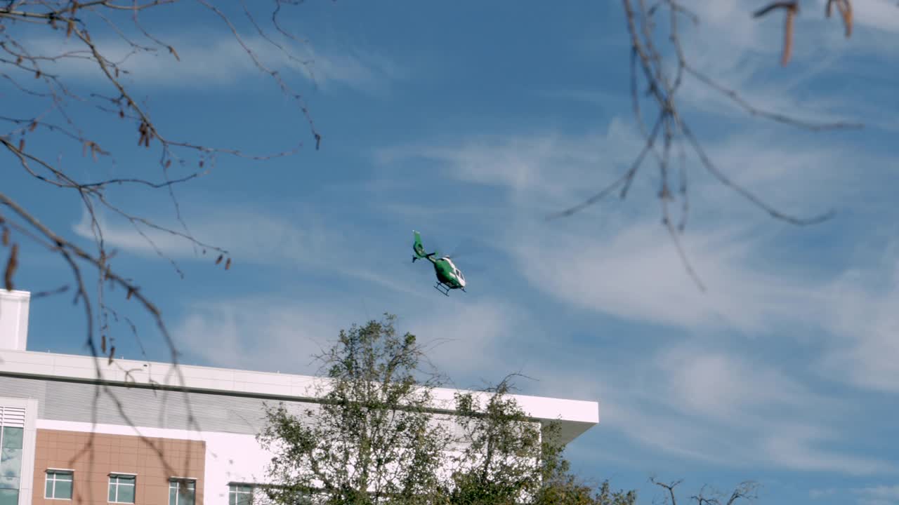 白天，绿白相间的医疗直升机离开医院屋顶视频下载
