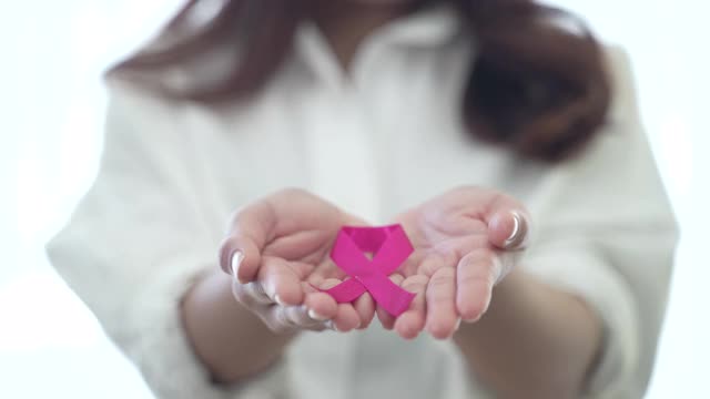 世界乳腺癌日的概念，年轻的亚洲妇女微笑着，手拿粉红丝带，看着相机，癌症的象征视频下载