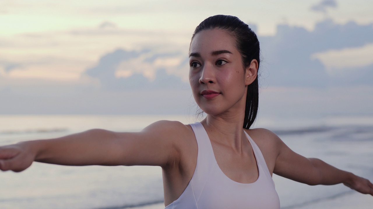正面观点健康年轻有吸引力的亚洲妇女练习瑜伽在户外战士姿势。视频素材