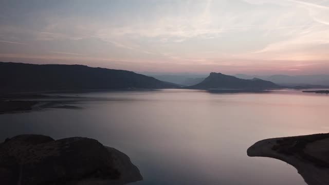在日落时分，空中拉回被群山包围的宁静峡谷视频素材