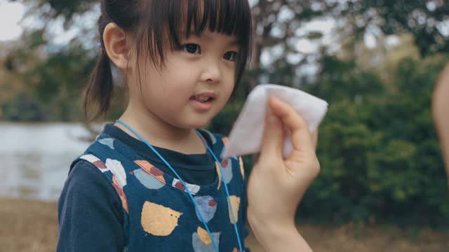 母亲拿着纸巾，帮助生病的女儿擦鼻子视频下载