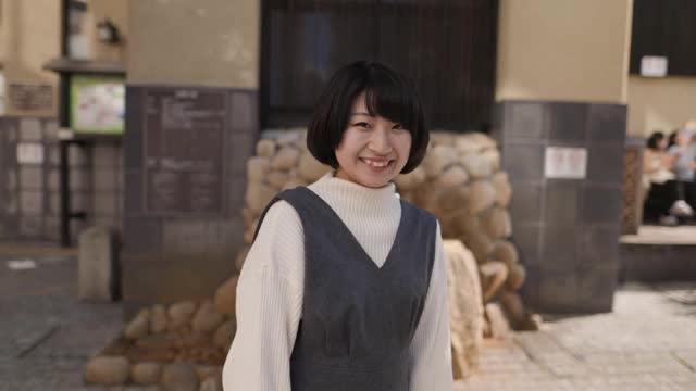 快乐的年轻女子站在“温泉”旅游地点的街道上视频素材