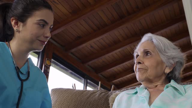 年轻护士在家庭保健访视中使用听诊器检查老年妇女的心跳视频下载
