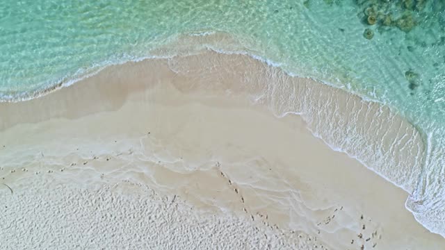 下面是加勒比海的一个白色沙滩的鸟瞰图。海浪和沙滩在海岸线上。视频素材