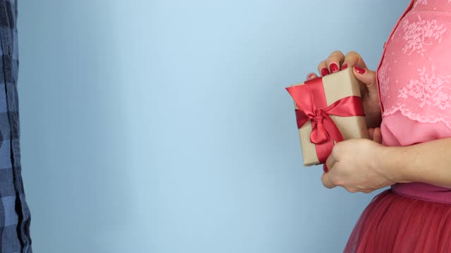 情人节，女人送礼物给男人。女人们手牵着手把包装好的礼盒和红色蝴蝶结送给心爱的男人们。生日礼物。节日的概念视频素材