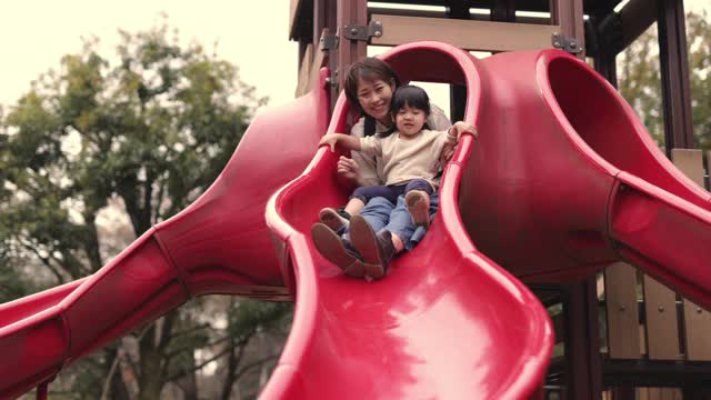 年轻的母亲和她的小女儿在公园玩滑块-第二部分视频素材