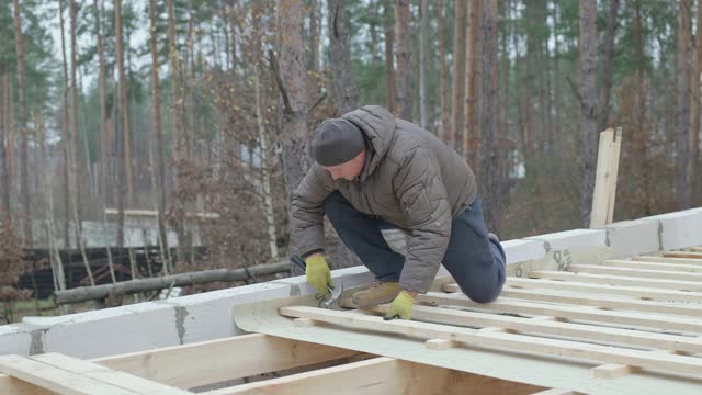 屋顶工人用锤子把钉子钉进木结构的屋顶上。视频下载
