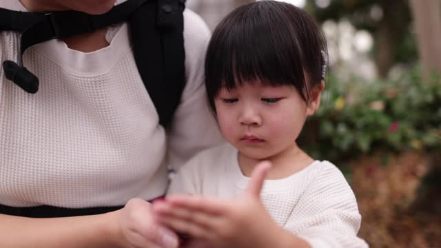 哭闹的小女孩和妈妈在公园里玩智能手机视频素材