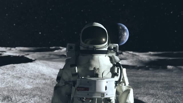 一名宇航员站在月球表面的环形山之间，以地球为背景。外太空。超逼真3d动画视频素材