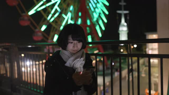 年轻女子在明亮的夜晚使用智能手机视频素材
