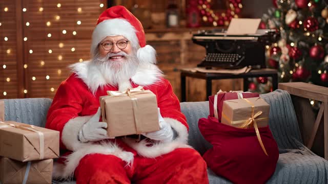 英俊的男圣诞老人给包好的礼盒祝贺圣诞。4k龙红相机视频素材