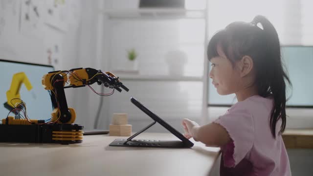 女孩在数字平板电脑上控制机器人手臂，在高中上机器人课视频素材