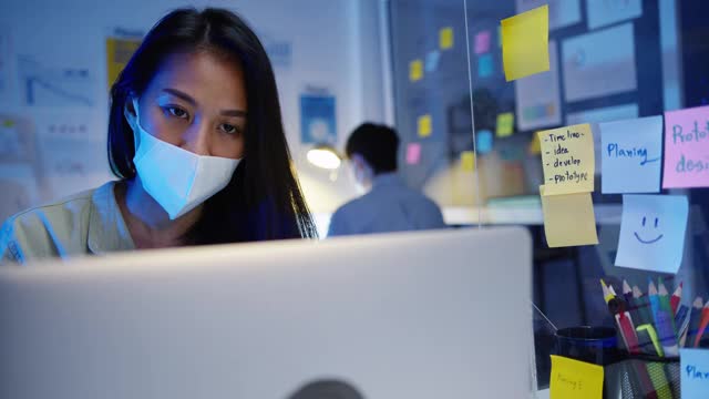 亚洲商界女性在新常态下保持社交距离，以预防在晚上工作时用笔记本电脑向同事演示视频通话计划。视频素材
