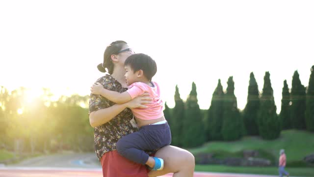 亚洲母亲在公园里抱着并亲吻她的男婴视频素材