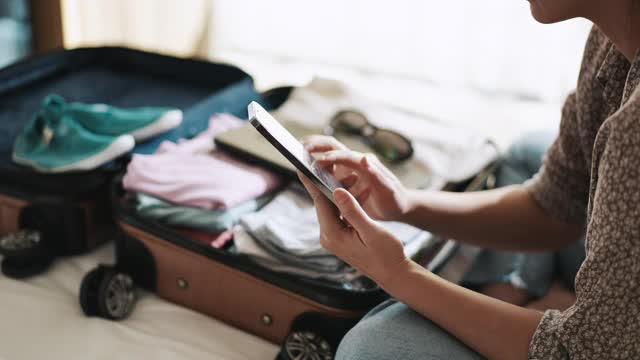 女性在智能手机上查看度假旅行箱清单视频下载