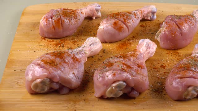 鸡腿在切菜板上洒上橄榄油。腌制肉类的过程。视频下载