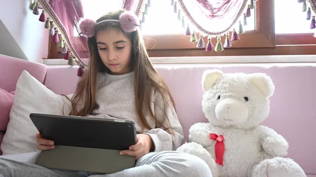 小女孩在家里用平板电脑视频下载
