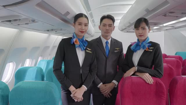 三个男人和女人的肖像在蓝色西装的空乘空中小姐在经济舱微笑欢迎乘客在飞机上。视频素材