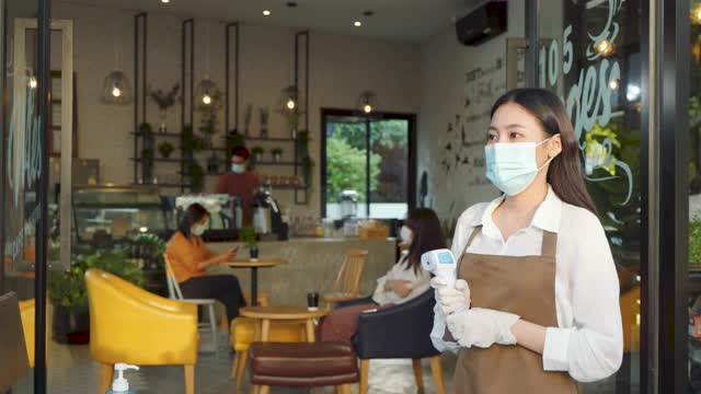 亚洲女性咖啡厅员工在量体温后戴口罩的亚洲男性在去餐厅或咖啡厅前，为了新冠肺炎大流行的正常生活方式。视频素材