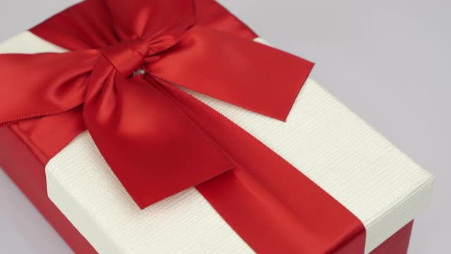 情人节节日惊喜。情人节礼物。白色礼盒与红色丝带蝴蝶结在白色背景下旋转。浪漫的问候。爱情和浪漫的概念视频下载