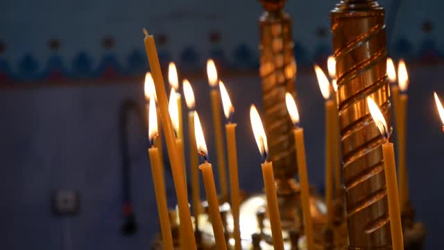 在东正教教堂里点燃蜡烛。在教堂的烛台和点燃的蜡烛为宗教项目。缓慢的运动。视频素材