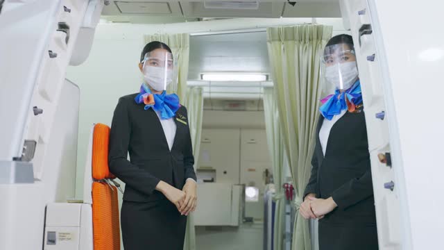 新冠肺炎疫情期间，亚洲空乘人员戴口罩迎接登机和步行的乘客，防止感染新冠肺炎。交通保健概念。视频素材