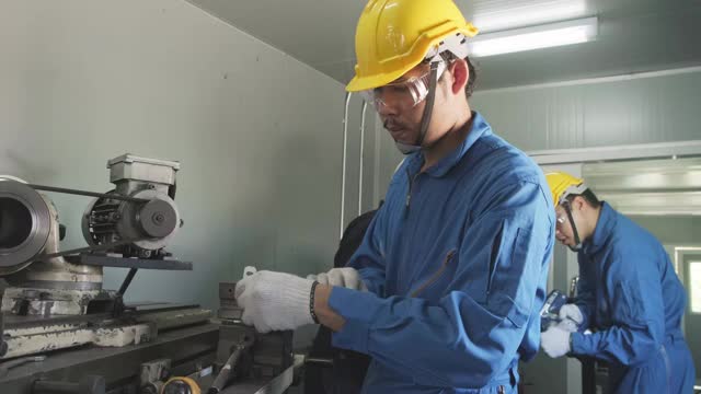 亚洲机械工人在铣床上工作。技术人员在操作机器时戴上防护眼镜和安全帽，以确保安全。这个人小心翼翼地工作，以防发生危险视频素材