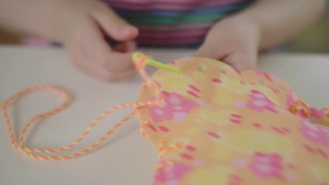 年轻女孩在家里用塑料针和纱线缝制垫子工艺视频下载