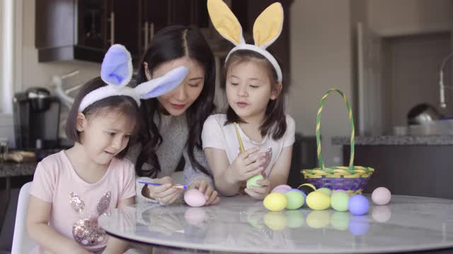 妈妈帮助两个亚裔女孩给复活节彩蛋着色视频下载